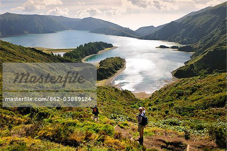 A couple walking along the big volcanic crater of Lagoa do Fogo (Fire Lagoon), a nature reserve and one of the most preserved sites in Sao Miguel. Azores islands, Portugal