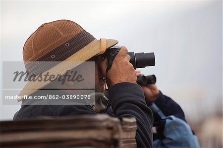 A man in a pith helmet watching game on the Serengetti in Tanzania