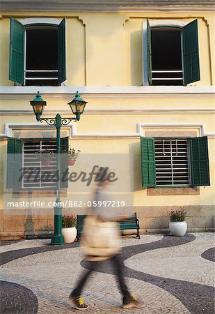 Woman walking past St Augustine's Church in St Augustine's Square, Macau, China