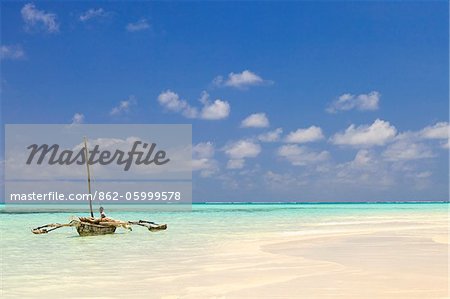 Tanzania, Zanzibar, Unguja, Jambiani. A man sits on his boat.