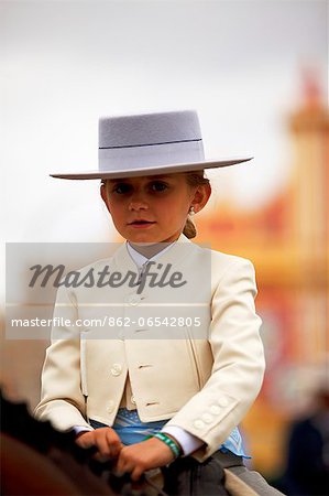 Seville, Andalusia, Spain, A Spanish girl in Traditional Andalusian clothes riding a horse during the Feria de Abril