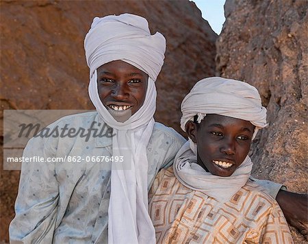Chad, Barakatra, Ennedi, Sahara. Two young Tubu boys fresh from riding their horses relax among rocks.