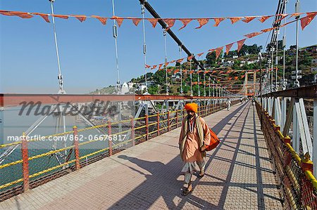 India, Madhya Pradesh, Omkareshwar. A Hindu pilgrim crosses a bridge at Omkareshwar, a sacred island in the Narmada River and an important pilgrimage destination.
