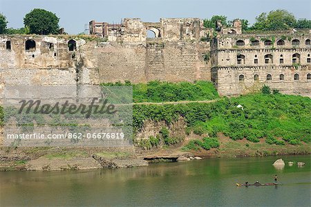 India, Madhya Pradesh, Burhanpur. Boatmen punt in the Tapti River beside the Shahi Qila, a medieval palace.