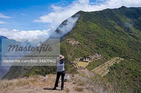 South America, Peru, Cusco, Choquequirao. A hiker looks out over terraces, plazas and buildings at the Inca city of Choquequirao, built by Tupac Inca Yupanqui and Huayna Capac and situated above the Apurimac valley with mountains of the Salkantay range