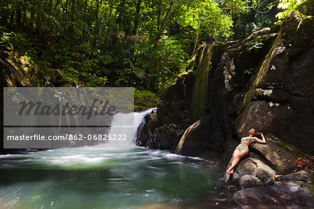 Dominica, Bense. A young woman lays on the rocks at La Chaudiere Pool. (MR).