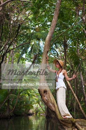 Dominica, Portsmouth. A young woman stands on a tree on the Indian River, one of Dominica's most popular tourist attractions. (MR).