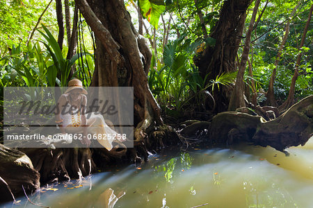 Dominica, Portsmouth. A young woman sits by the Indian River, one of Dominica's most popular tourist attractions. (MR).