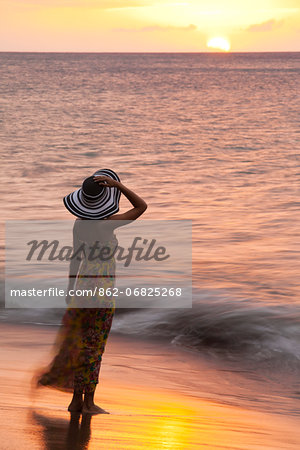 Dominica, Portsmouth. A young woman watches the sun set from Coconut Beach. (MR). Dominica, Portsmouth. A young woman watches the sun set from Coconut Beach. (MR).