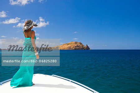Dominica, Soufriere. A young woman stands on the foredeck of a Powerboat near Soufriere, looking at Scott's Head - a distinctive landmark of Dominica. (MR).