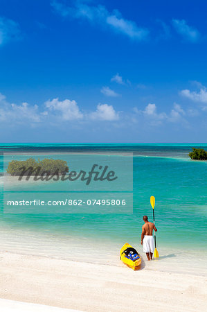 Central America, Belize, Belize district, Little Frenchman Caye, Royal Palm Island, a young man with a kayak looks out to the Caribbean Sea