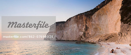 Western Europe, Greece, Ionian Islands, Paxos. Tourists watching the sunset on Erimitis Beach.