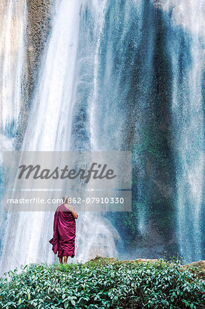 Myanmar, Mandalay division, Pyin Oo Lwin. Burmese monk praying under Dattawgyaik Waterfall (MR)