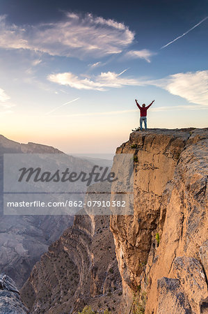 Oman, Wadi Ghul, Jebel Shams. The Grand canyon of Oman, tourist on the edge looking at view, at sunrise (MR)