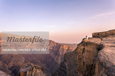 Oman, Wadi Ghul, Jebel Shams. The Grand canyon of Oman, tourist on the edge looking at view, at sunset (MR)