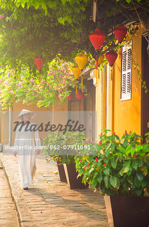 Woman wearing Ao Dai dress walking along street, Hoi An (UNESCO World Heritage Site), Quang Ham, Vietnam (MR)