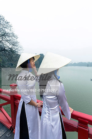 Vietnam, Hanoi, Hoan Kiem lake. Young vietnamese girls in traditional Ao Dai dress (MR)