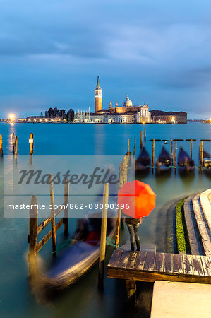 Italy, Veneto, Venice. Woman with red umbrella on Riva degli Schiavoni at dawn (MR)