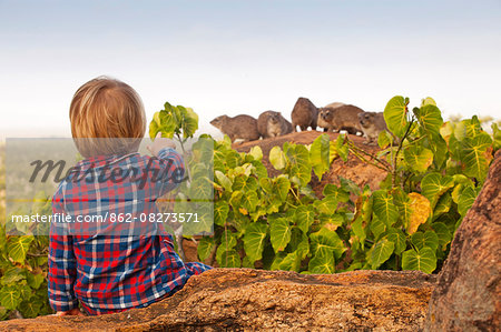 Kenya, Meru. A young boy spots rock dassies in his pyjamas early in the morning.