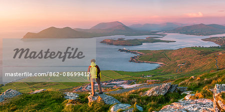 Valentia island (Oilean Dairbhre), County Kerry, Munster province, Ireland, Europe. Panoramic view of a man watching sunset from the Geokaun mountain and Fogher cliffs.