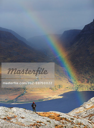 Scotland, Highland, Torridon. A hiker beneath a rainbow on the Beinn Eighe mountain trail. MR