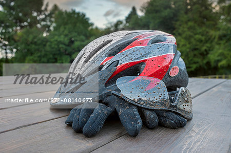 Mud spattered cycle helmet with glasses and gloves.