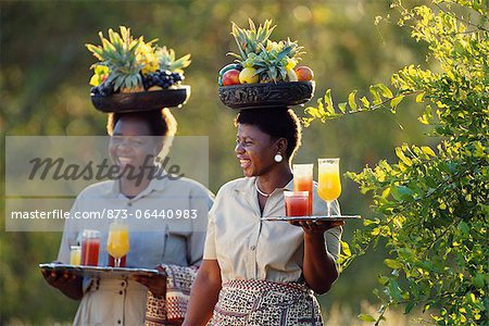 Two Waitresses Carrying Cocktails And Fruit
