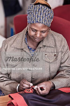 African woman sewing some fabric, smiling