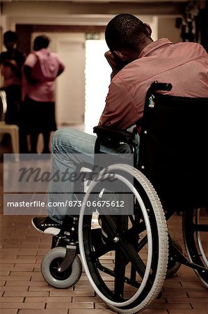 African man sitting on a wheelchair in a clinic corridor