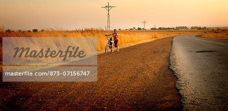 Boy pushing bicycle along South African roadside