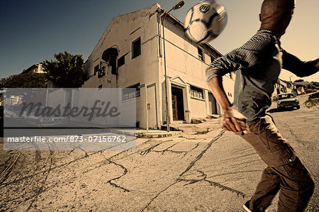 Boy playing soccer on the street