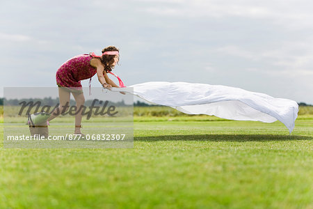 Young woman setting a sheet on the grass, oudoors