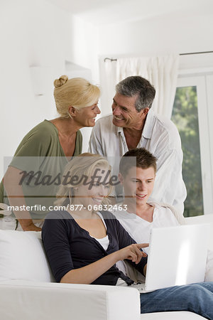 Mature couple and young couple at home, looking at laptop