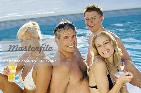 Mature couple and young couple sitting near a pool