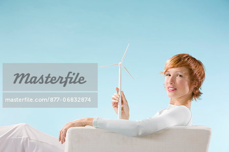 Woman looking at the camera, éolienne in hand in a clear blue background