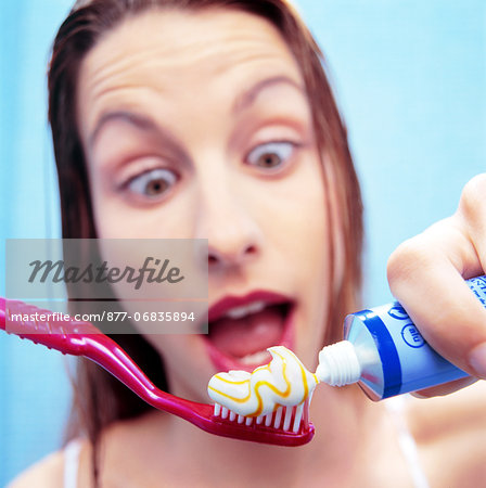 Portrait surprised woman putting toothpaste on toothbrush