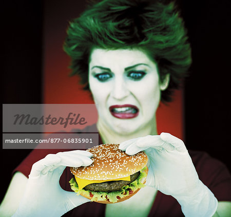 Portrait of woman holding hamburger with gloved hands, looking disgusted, blue eyes, green hair