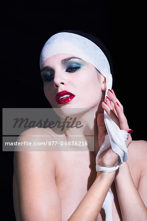 Naked woman removing bandages from her head