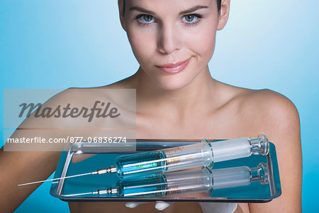 Young woman holding tray with syringe