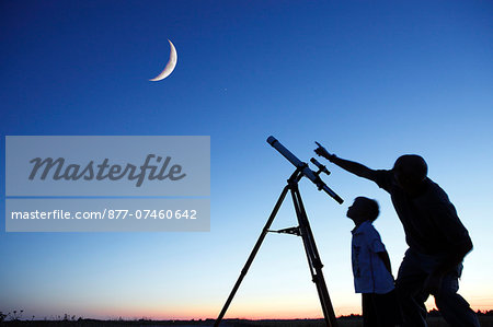 Seine et Marne. A father and his 6 year old son in the process of observing the moon in a telescope.