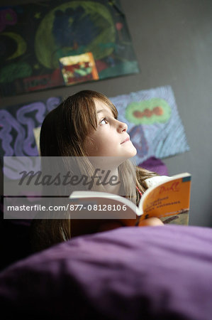 A 9 years old girl reading on her bed