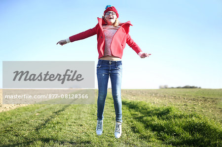A 10 years old girl jumping in the air on a country road