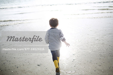 3 years old boy playing in the water at the beach