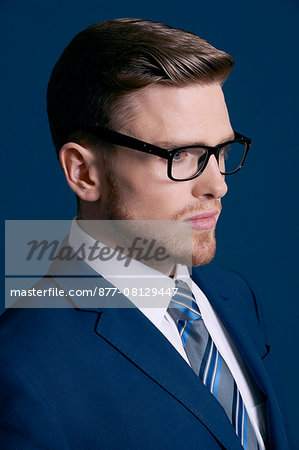 man in blue suit, tie, beard; blue background, glasses man in blue suit, tie, beard; blue background, glasses