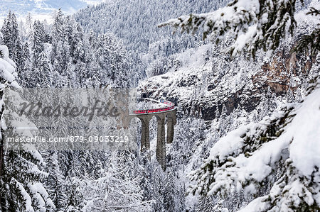 The Bernina Express red train as it passes over the Landwasser bridge, Filisur, Graubunden, Switzerland, Europe.