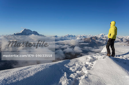 Europe, Italy, Veneto, Belluno. Hikers in winter on top of Mount Pore looking to the landscape