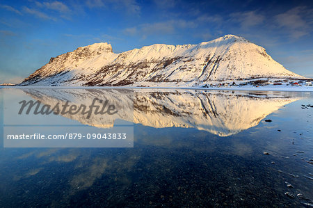 The snow capped mountains reflected in Steiropollen lake at sunrise. Lofoten Islands. Norway Europe