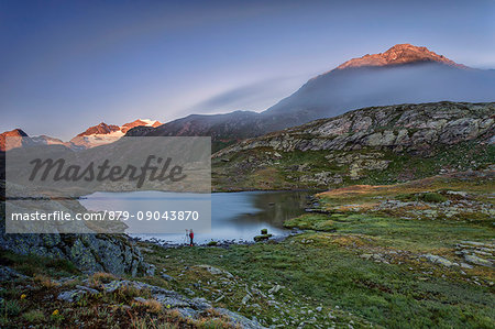 Photographer in action on the shore of the alpine lake at dawn Minor Valley High Valtellina Livigno Lombardy Italy Europe