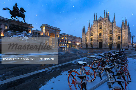 Bicycles parked in PIazza Duomo during snowfall at dusk. Milan, Lombardy, Northern Italy, Italy. Bicycles parked in PIazza Duomo during snowfall at dusk. Milan, Lombardy, Northern Italy, Italy.