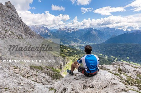 Europe, Italy, Veneto, Agordino, Mountaineer observes the panorama at the end of the ferrata Stella Alpina on Mount Agner, Pale di San Martino, Dolomites